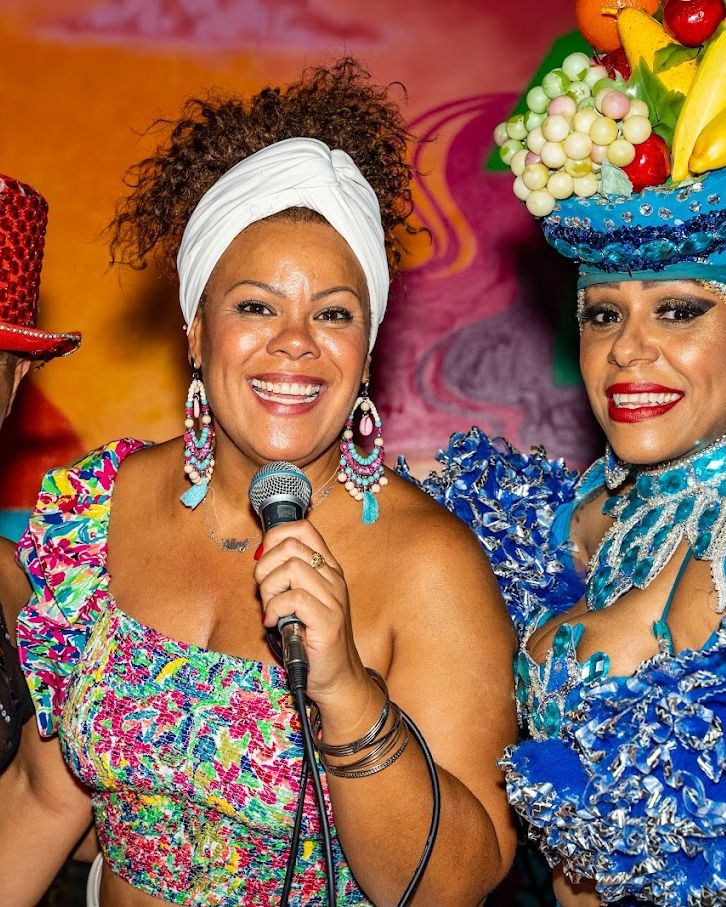 Una cantante con il microfono e due ballerini in costume durante una serata brasiliana da Maria Bonita